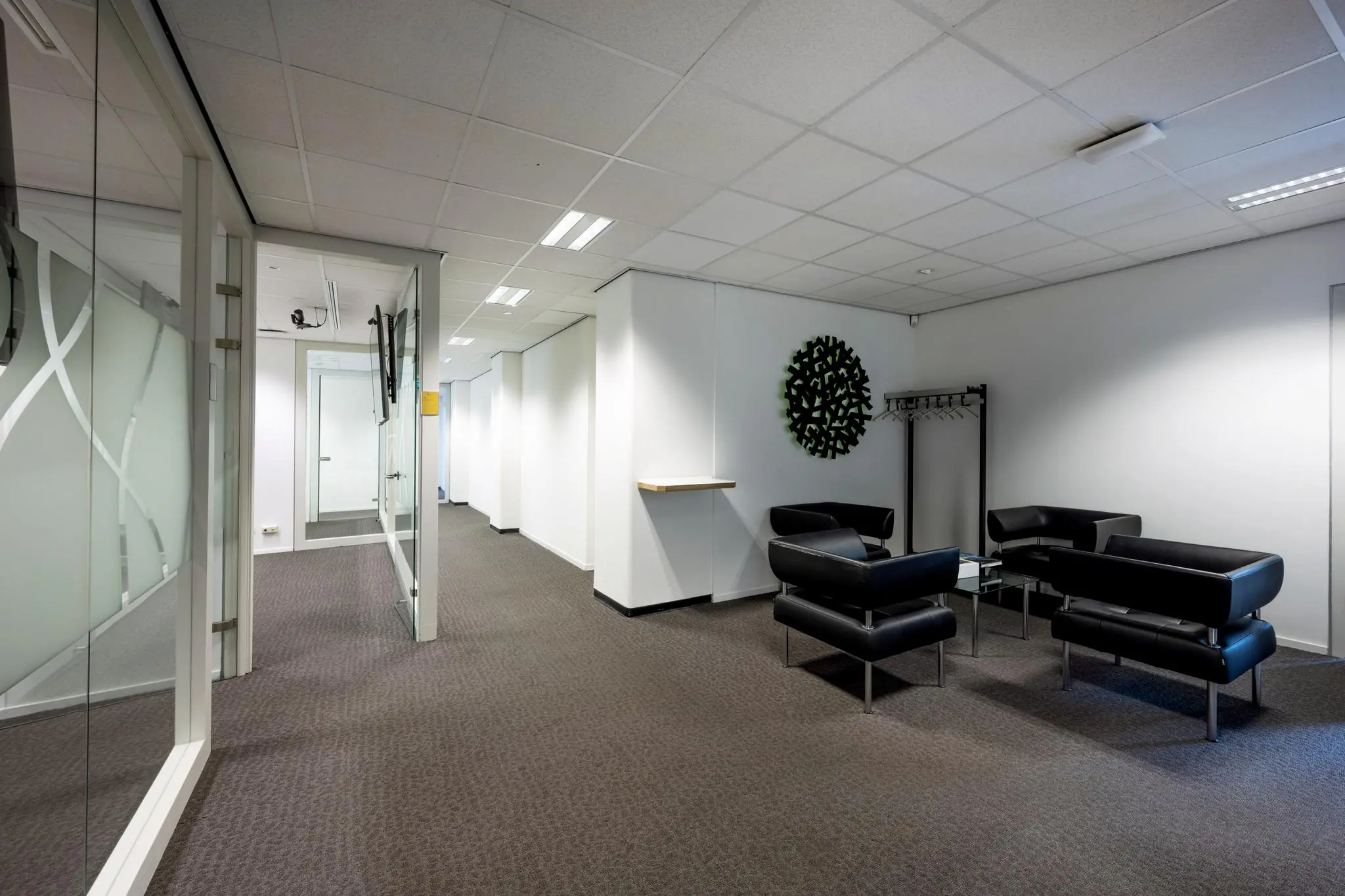 Moderne wachtruimte in een kantoorgebouw aan de Jan Tooropstraat met zwarte lederen stoelen, glazen tafel en strakke inrichting.